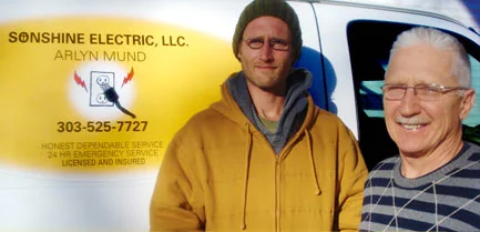 Arlyn Mund, right, and Seth Mund, left, standing in front of a Sonshine Electric van