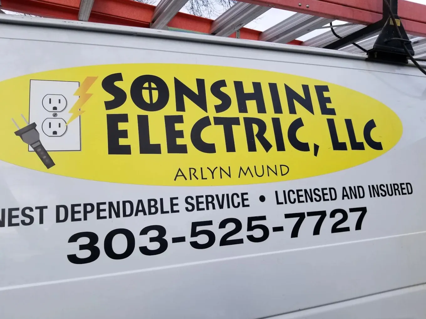 The Sonshine Electric work van: a yellow oval decal reading Sonshine Electric, LLC, Arlyn Mund, with Honest Dependable Service, Licensed and Insured and 303-525-7727 lettered below